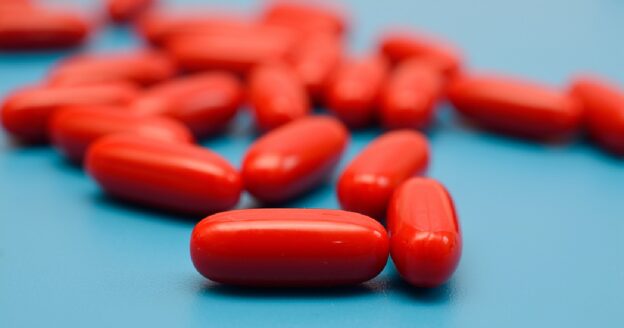 Red supplement capsule pills on blue background